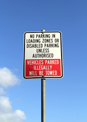 No Parking road sign against a blue sky with clouds background