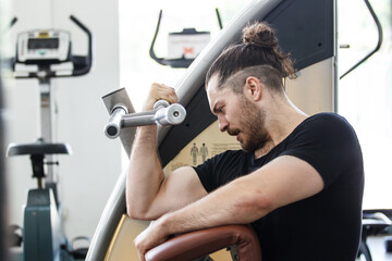 Hispanic man doing a weight training exercise in the gym.