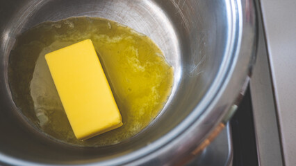 A stick of butter melting in a pot cooking close up