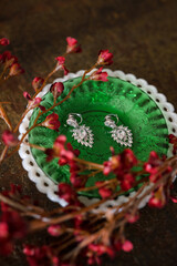 diamond wedding earrings on green plate with red flowers