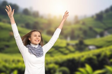 Happy woman raising arms enjoying on the green hill