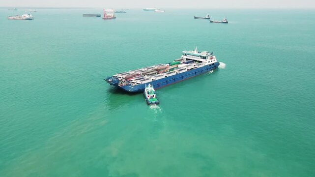tugboats are pushing car carrier. Car ferry leaving docks fully loaded.