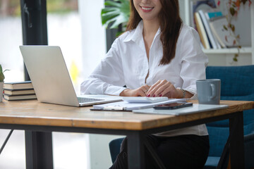 Beautiful business woman Happy working online shopping at her store. Through phone, computer, young woman seller prepares parcel boxes to send to customers. online sales ecommerce