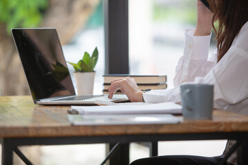 Beautiful business woman Happy working online shopping at her store. Through phone, computer, young woman seller prepares parcel boxes to send to customers. online sales ecommerce