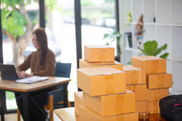 Beautiful business woman Happy working online shopping at her store. Through phone, computer, young woman seller prepares parcel boxes to send to customers. online sales ecommerce