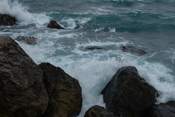 Turquoise sea stone beach, breaking waves on a cloudy spring day. Beautiful sea background. The concept of summer, vacation, travel. The purest clear sea water, large stones on the beach close-up