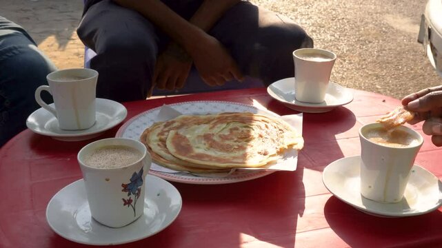 At a local dhaba restaurant, a group of friends enjoying breakfast with tea and parathas.