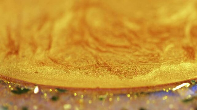 Liquid gold. Glitter fluid spill. Defocused yellow color shimmering metallic sequin particles acrylic paint ink drip motion abstract art background with bokeh lights.