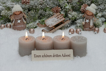 Dritter Advent: Dekoration mit vier grauen Adventskerzen und Weihnachtsschmuck im Schnee.	