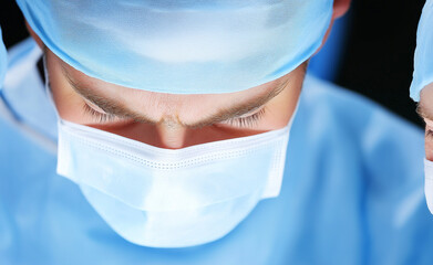 Surgeons preparing for an operation in a sterile, well-lit operating room with overhead lights.