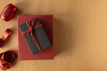 Top view, black gift box tied with a red rope over red gift box on brown background. Concept for holiday with copy space.