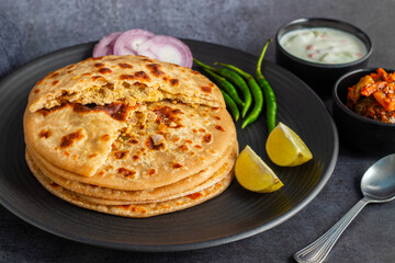 Sattu paratha, a stuffed flatbread from Uttar Pradesh and Bihar, is filled with spiced roasted gram flour and served with pickle and raita.