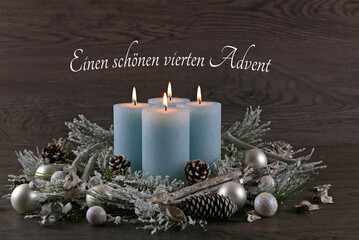 Dekoration zum vierten Advent: Adventskranz mit hellblauen Kerzen, Weihnachtskugeln und dem Text...