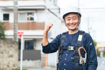 作業員、シニア、高齢者、笑顔、仕事、ガッツポーズ、建設、工事、元気、がんばる、努力、やりがい、充実、満足、やる気、モチベーション、生きがい、アルバイト、シルバー人材、再雇用、安全、ヘルメット、インフラ、建築、住宅、職人、大工、フルハーネス、電力、電気、技師、エンジニア、住宅街、チャレンジ、挑戦、働く、現場、高所作業、日本人、男性、パワー、パワフル、体力、労働者、定年、業者、工務店、修繕、修理、人物