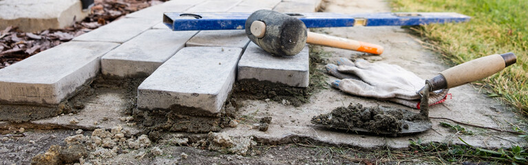 Laying paving stones on cement mortar. banner. Laying a garden path made of tiles. Self-laying of concrete paving slabs in the courtyard of the house. do it yourself. DIY