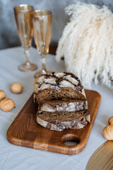 A beautiful goldenbrown loaf of freshly baked bread rests elegantly on a wooden cutting board placed on a rustic dining table, eagerly waiting to be sliced and enjoyed by everyone around