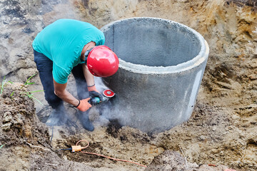 Angle grinder with diamond blade disc for concrete cutting is used during installation of septic tank.