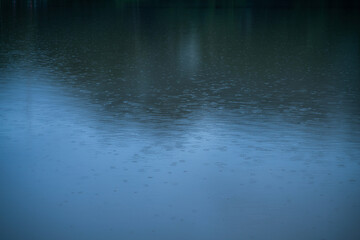 ฺBeautiful Reflected the Rain falls on the water surface in nature forest Mountain natural atmosphere rain fog sky abstract with white clouds background.