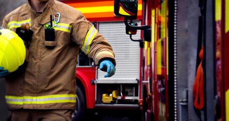 Firefighter in action with hand reaching for fire truck door. An emergency services fireman and two...