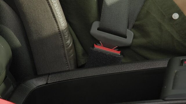 Close-up of black male hand buckling up seat drivers seat belt for safety drive during road trip.