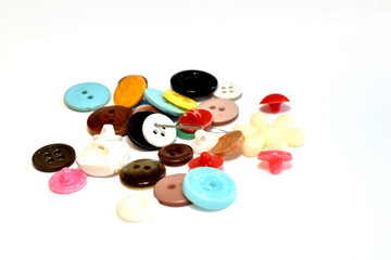 A mountain of buttons of different colors and shapes lies on a white background.