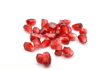 Red juicy pomegranate fruit grains lie on a white background.