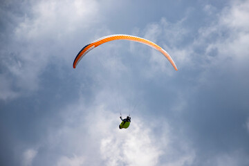 A man with a paraglider in front of a blue sky.