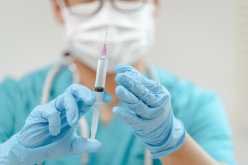 Close-up of a doctor's gloved hands preparing a syringe, focusing on the needle and liquid inside, with a sterile background, symbolizing medical professionalism.