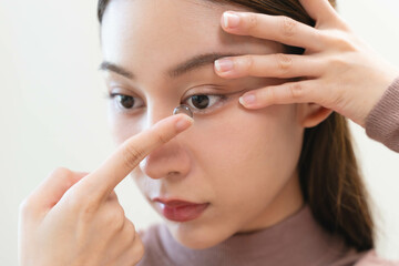 Close-up shot of woman putting contact lens in her eyes