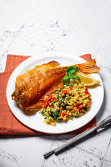 Baked fillet of red sea bass or perch fish with a side dish of bulgur and vegetables vertical photo