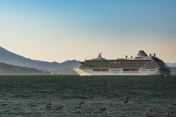 Luxury cruiseship cruise ship liner Serenity sail away departure from San Francisco port through bay towards Golden Gate Bridge on sunny day