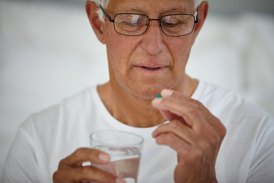 Senior man, drinking medicine and water in assisted living facility as patient with Alzheimers. Elderly person, prescription and pills in retirement home for treatment, support and healthcare service