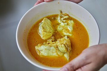 Cropped hand holding sour soup with snapper fish in bowl