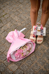 Soft pink blooms, a white handbag, and bare legs harmonize.