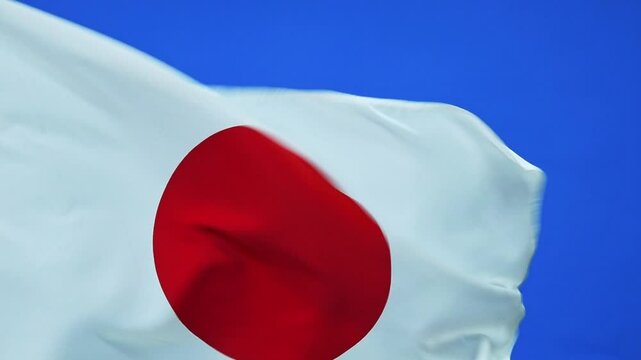 Slow motion video of Japan flag waving on blue background