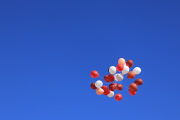 A bunch of colorful balloons against a blue sky with clouds.