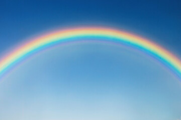 Multi-colored rainbow in a clear blue sky.