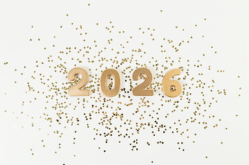 2026 Happy New Year. Top view of gold numbers, gold stars confetti on white background. Copy space, flat lay.