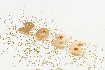 2026 Happy New Year. Top view of gold numbers, gold stars confetti on white background. Copy space, flat lay.