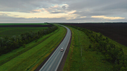 The car is driving along the road at dawn