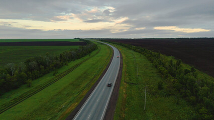 The car is driving along the road at dawn