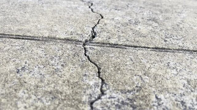 A closeup view focusing on a cracked and damaged concrete surface with intricate details