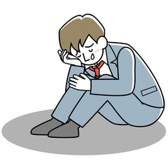 膝を抱えて泣く男性