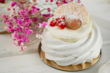 Meringue dessert with fruits. White dessert on a light table.