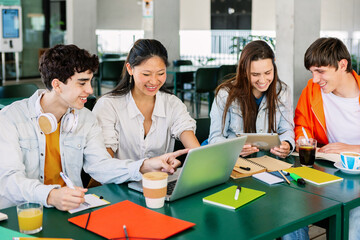 Diverse group of college students studying together at university cafeteria. Happy classmate...