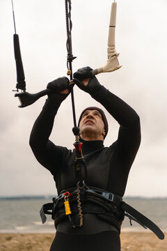 Middle aged man kite surfing, holding a bar in his hands