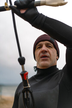 Middle aged man kite surfing, holding a bar in his hands