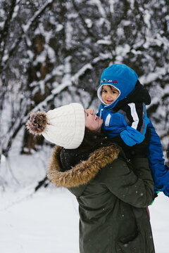 Latino baby with mom in snow covered forest in winter wonderland