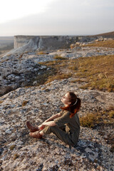 Woman sitting on rock in field gazing at sky in serene moment of tranquility and meditation