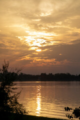 Fototapeta premium Golden sunset over a serene lake with silhouetted trees, perfect for calming retreats or nature-themed relaxation concepts